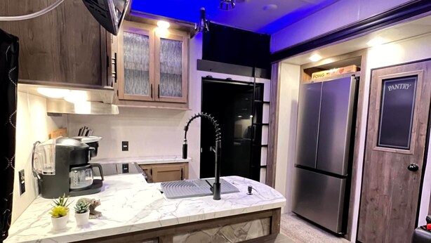 A modern kitchen with a marble countertop, a built-in stove, and a wooden bench. - The Bear Retreat at Venus (Highlands County)
