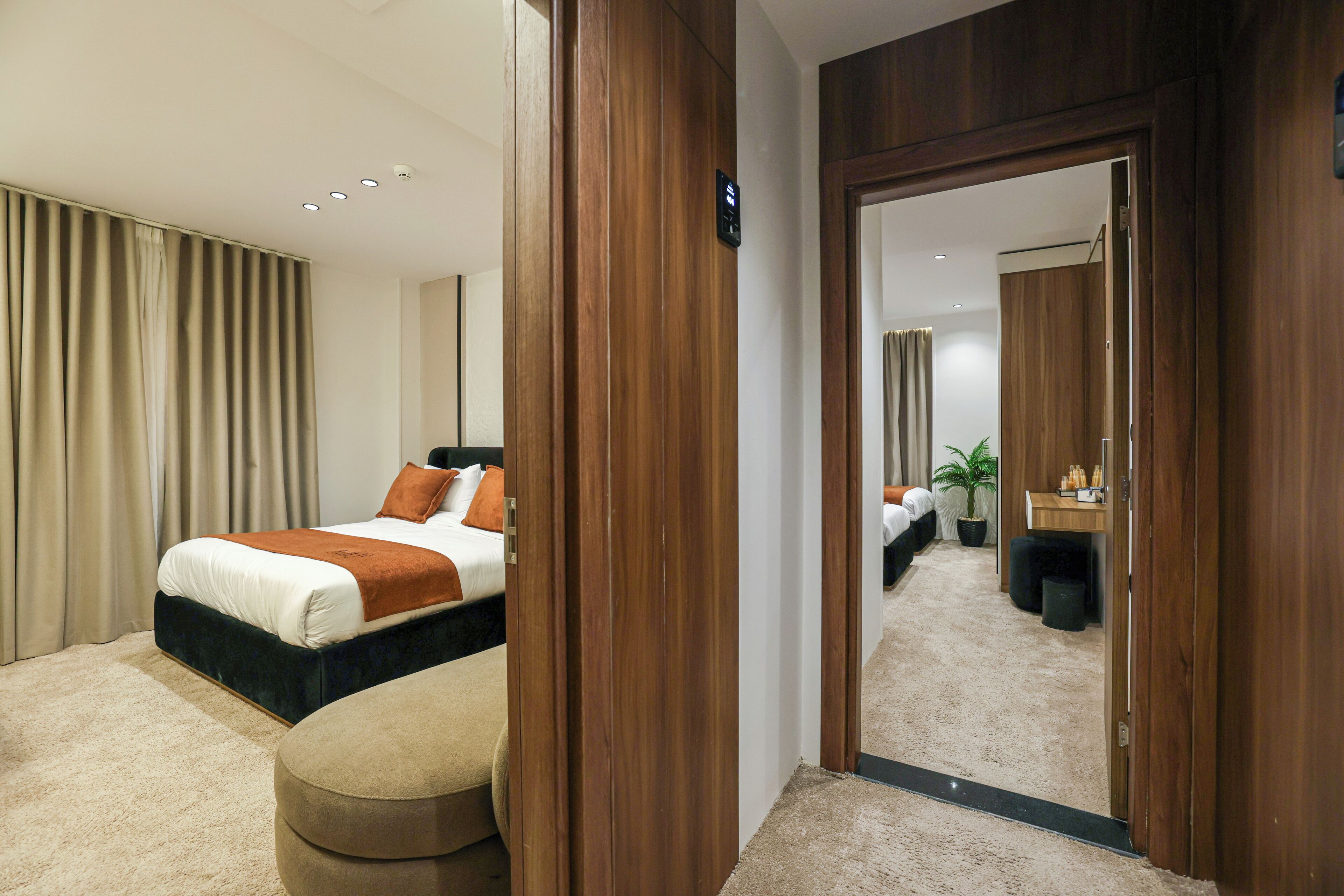 A modern hotel room with a large bed, a seating area, and a mirror reflecting the room.