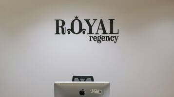 A white wall with the text 'ROYAL regency' and a laptop on a desk.