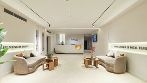 A modern reception area with a reception desk, two sofas, and a coffee table. - Royal Regency Hotel EG (New Cairo)