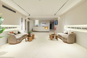A hotel lobby with a reception desk, two sofas, and a coffee table.