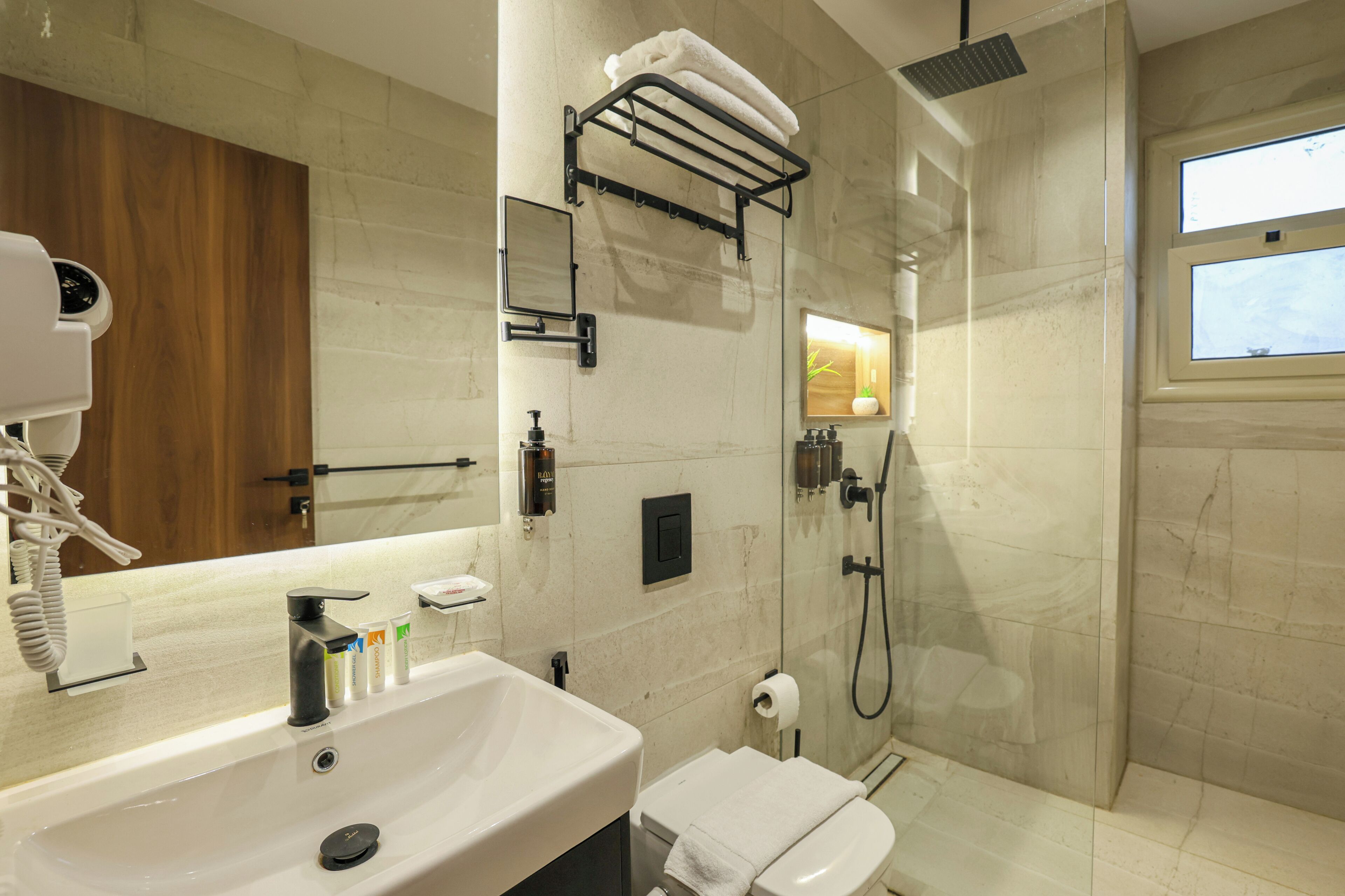 A modern bathroom with a large mirror, a sink, a toilet, and a shower area.