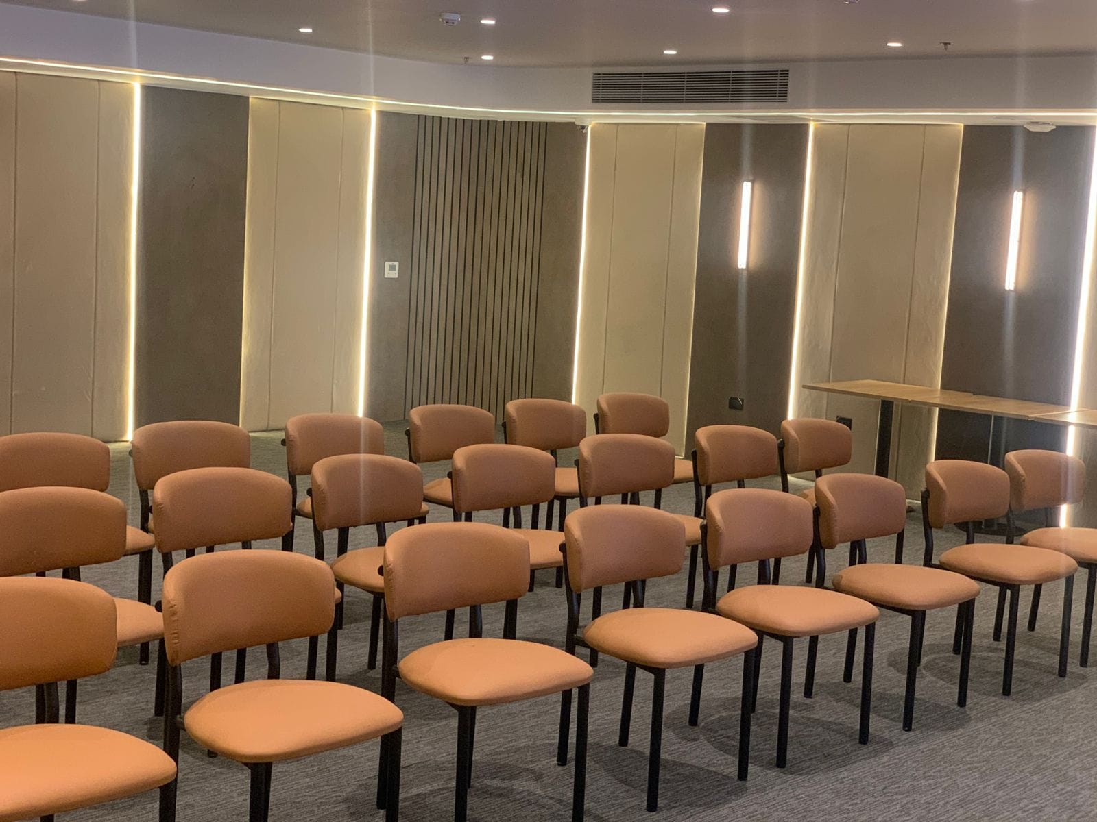 A conference room with rows of chairs, a podium, and a patterned wall.