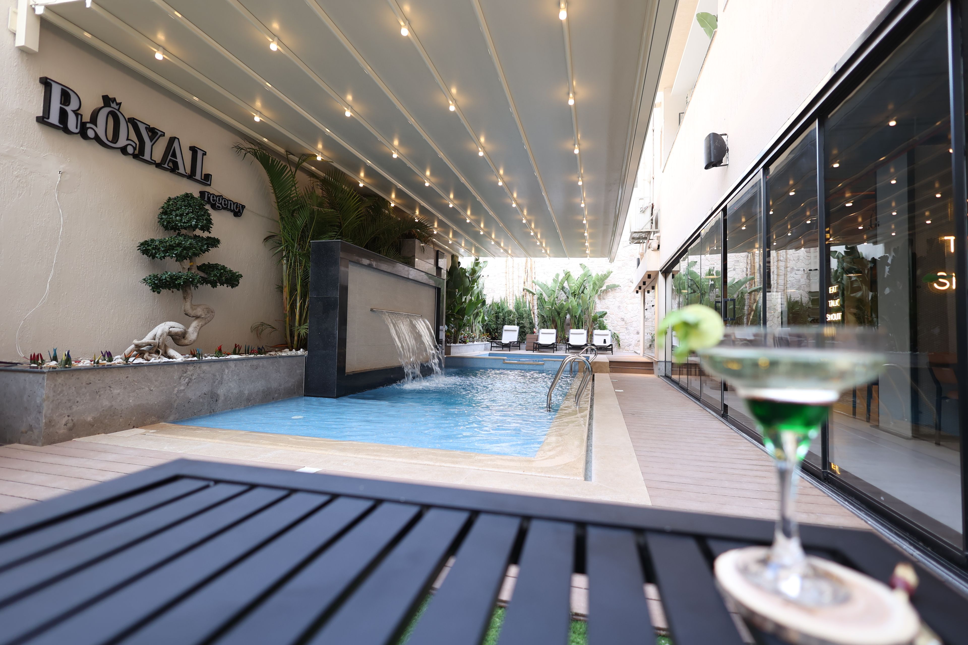 A rooftop pool area with a sign reading 'ROYAL regency' and a bar area with a martini glass.