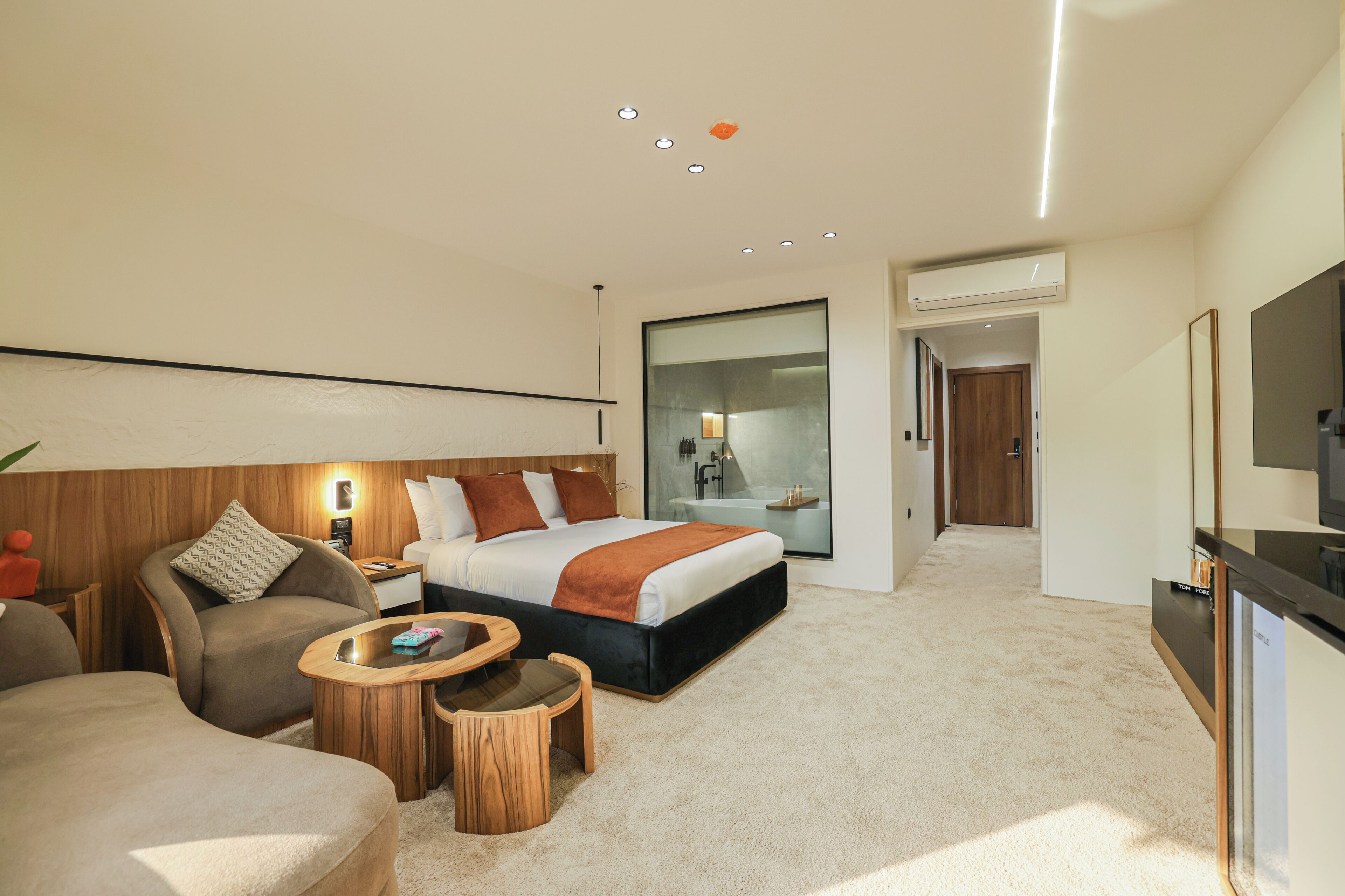 A modern hotel room with a large bed, a sofa, a small table, and a TV.