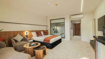 A modern hotel room with a large bed, a sofa, a small table, and a TV.