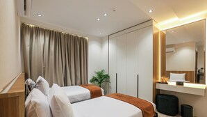 A modern hotel room with a bed, bedside table, mirror, and a small desk with a lamp. - Royal Regency Hotel EG (New Cairo)