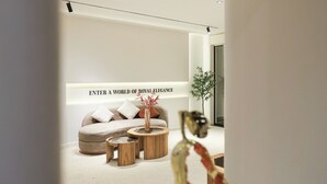 A modern living room with a sofa, two wooden side tables, and a decorative vase. - Royal Regency Hotel EG (New Cairo)