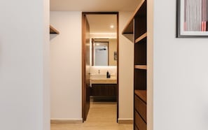 A narrow hallway leading to a bathroom with a sink and mirror.