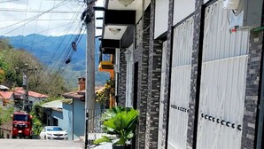 Un edificio moderno con un paseo techado, muro de piedra y vistas del entorno.