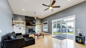 A spacious living room with a black leather sofa, a fireplace, and a ceiling fan. - WATER FRONT PROPERTY WITH PRIVATE BOAT DOCK (Ferndale)