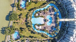 An aerial view of a resort with multiple swimming pools, palm trees, and a large building. - Destin West Gulfside 305 ~ Ocean Views ~ Beach Service (Fort Walton Beach)