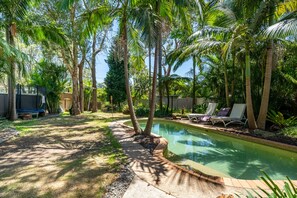 A backyard with a swimming pool, palm trees, and lounge chairs. - Vivid Sanctuary by Lake Beach, heated Pool EV Charger Fireplace 1hr from sydney (Gwandalan)