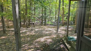 A covered outdoor area with a bench, surrounded by trees and a picnic table. - Creek Comfort! Charming sleeps 6 condo in lovely Bellaire. Short drive to skiing (Bellaire)