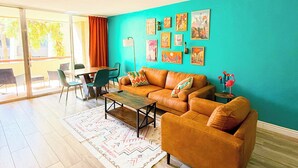 Un salón con una pared de acento color aguamarina, un sofá marrón, una mesa de centro y una alfombra estampada.
