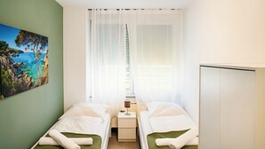 A small, clean room with two single beds, a nightstand, a lamp, and a wardrobe. - City apartment no. 13 with comfort (Pforzheim)
