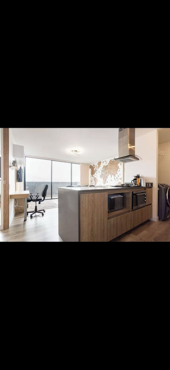 A modern kitchen with a large island, built-in appliances, and a view to the outside.