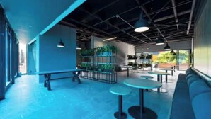 A modern interior with a high ceiling, exposed beams, and a seating area with tables and benches.
