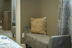 A bedroom with a grey sofa, a patterned pillow, a bedside table, and a mirror. - Private Pool, Fire pit, Pet-friendly Home (Panama City)