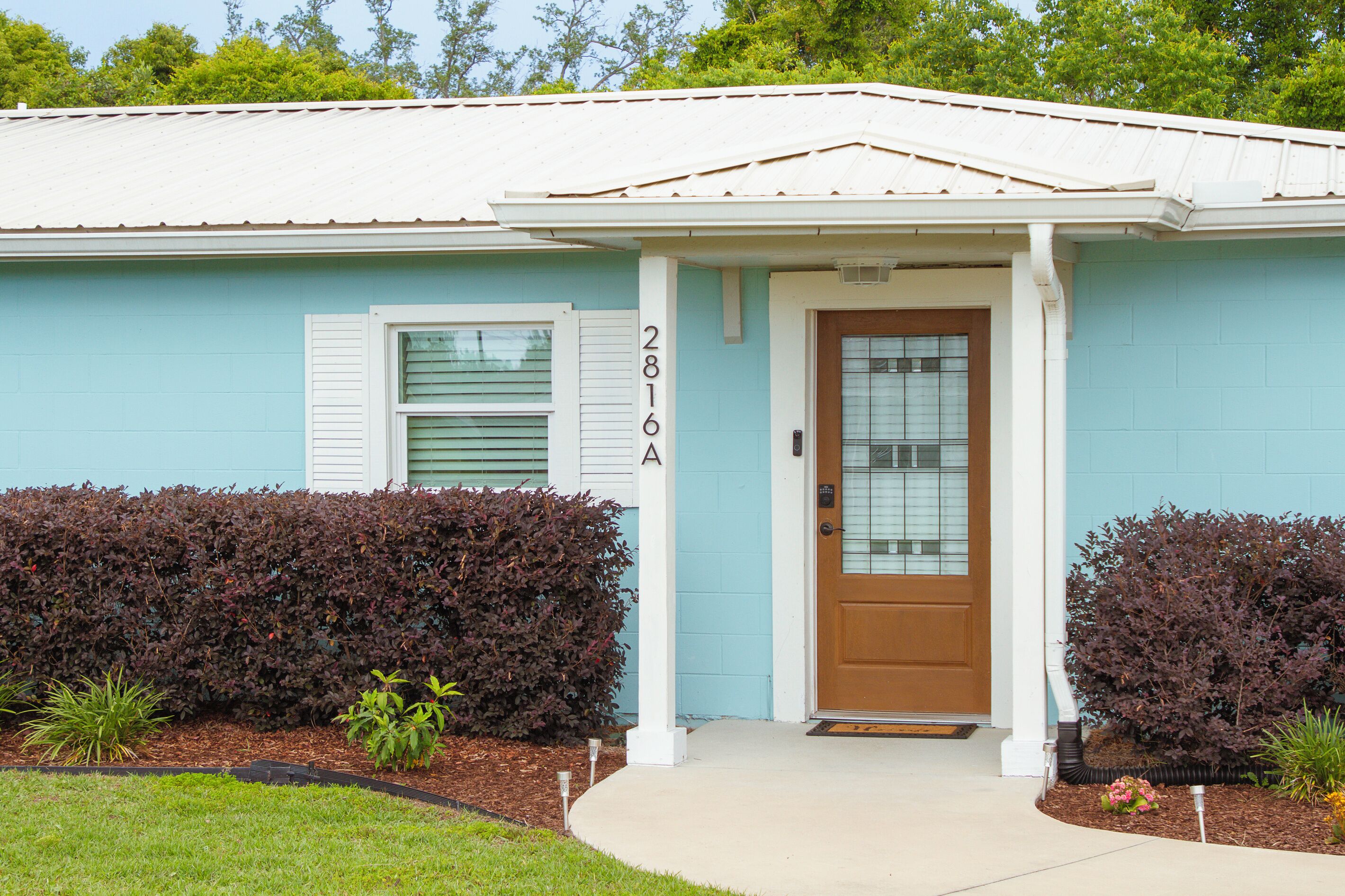 A single-story house with a blue exterior, a brown front door, and a mailbox.