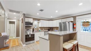 Une cuisine moderne avec des armoires blanches, des appareils électroménagers en acier inoxydable et un coin bar.