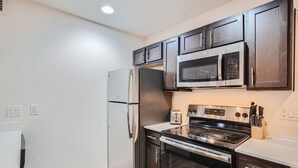 A kitchen with dark wooden cabinets, stainless steel appliances, and a white countertop.