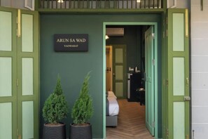 Entrada de hotel con un letrero que dice 'ARUN SA WAD' y un pasillo que conduce a una habitación.