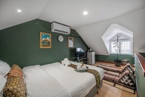 Un dormitorio con cama, escritorio, silla, televisor y ventana.