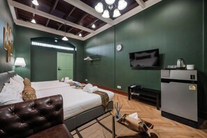 Un dormitorio con una cama doble, televisión, refrigerador y escritorio.
