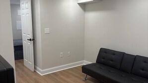 A modern living room with a black sofa, wooden flooring, white walls, and recessed ceiling lights. - Peaceful retreat in west Baltimore (Baltimore)