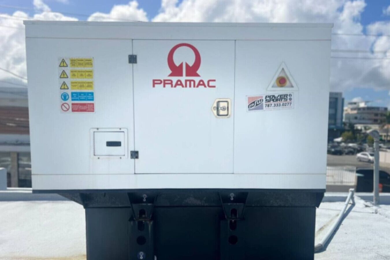 A white electrical box with the PRAMAC logo, warning labels, and a contact number for DWM Sports.