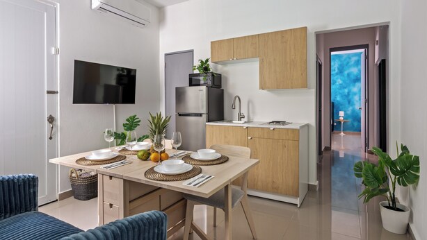 Une cuisine moderne équipée d’un téléviseur à écran plat, de meubles en bois et d’un coin repas avec une table mise pour deux personnes.