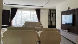 A modern living room with a sofa, a TV, and a window with curtains.