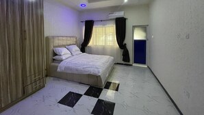 A bedroom with a bed, a wardrobe, a window with curtains, and a door.