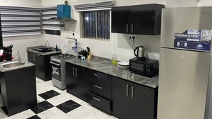 A modern kitchen with black cabinets, a gas stove, a sink, and a refrigerator.