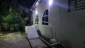 A building with a concrete exterior, a set of stairs leading to a door, and a small garden area with plants.