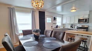 Un comedor moderno con una mesa de madera, sillas tapizadas de color gris y un florero decorativo como centro.