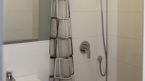 Un baño con ducha, lavabo y espejo.