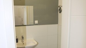 Un baño pequeño y limpio con lavamanos, inodoro y espejo.