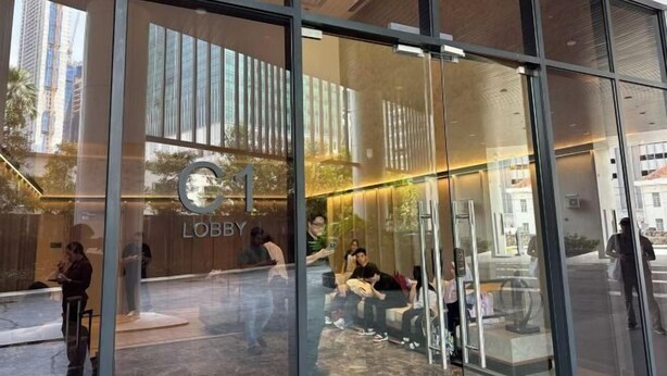 A modern lobby with glass walls, a wooden reception desk, and seating areas. - Agile Luxury Suite at TRX KLCC (Kuala Lumpur)