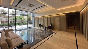 A modern hotel lobby with a glass partition, a seating area with a sofa, and a corridor leading to rooms. - Agile Luxury Suite at TRX KLCC (Kuala Lumpur)