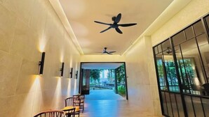 A hallway with a ceiling fan, a seating area with chairs, and a view of an outdoor area. - Agile Luxury Suite at TRX KLCC (Kuala Lumpur)