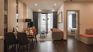 A modern hotel room with a dining area, a sofa, and a view through a glass door. - Masteri West Height - Vinhomes SmartCity - HanoiHomes (Hanoi)