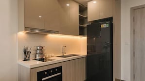 A modern kitchen with a black refrigerator, stainless steel sink, and wooden cabinets. - Masteri West Height - Vinhomes SmartCity - HanoiHomes (Hanoi)