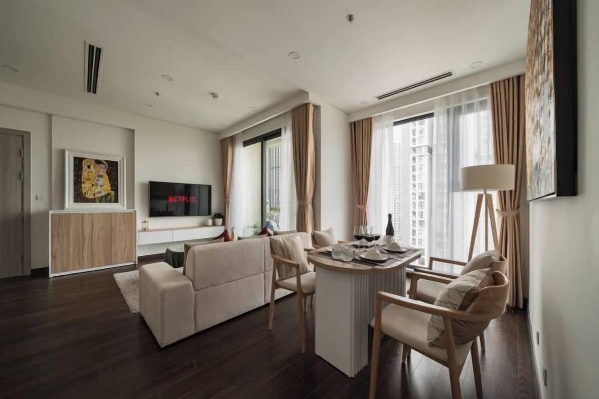 Quarto de hotel moderno com área de estar, mesa de jantar e televisão.