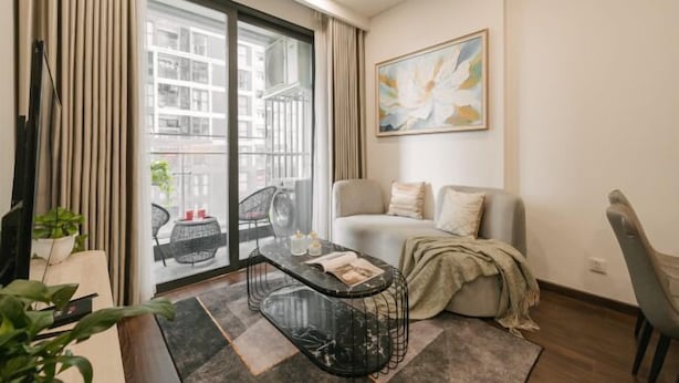 A modern living room with a sofa, a coffee table, and a painting on the wall. - Masteri West Height - Vinhomes SmartCity - HanoiHomes (Hanoi)
