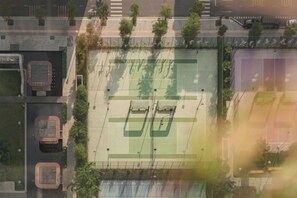Une vue aérienne d’un terrain de sport entouré d’arbres et d’immeubles.