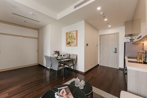 A modern living room with a dining area, a kitchen, and a door leading to another room.