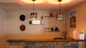 A kitchen with a stone countertop, three stools, hanging pendant lights, and a popcorn machine. - Wellness Retreat • Sauna•Cold Plunge•Pool•Golf•Spa (Scottsdale)