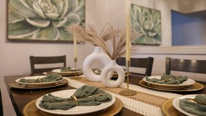 A dining table set with plates, napkins, and candles, surrounded by chairs. - Wellness Retreat • Sauna  •Cold Plunge•Pool•Golf•Spa (Scottsdale)